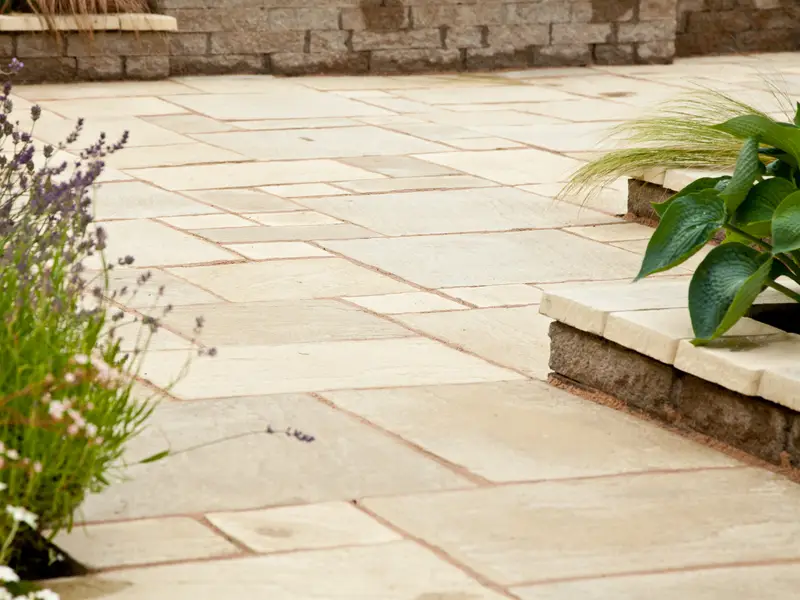 Riven Indian sandstone paving in buff and cream tones beside a dry stone edge