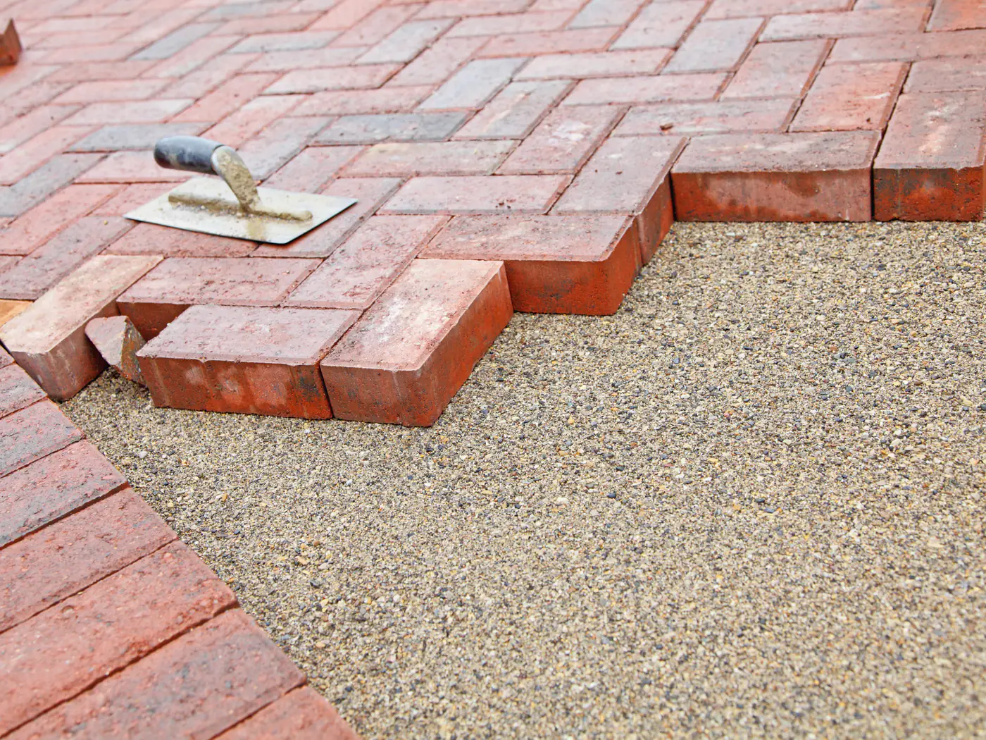 Block paving being laid onto its bed against a concrete-set edging